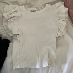 Vit topp med volanger - Söt vit topp med volanger från Zara. Fint skick, knappt använd och inga fläckar. Kom privat vid frågor. Använd gärna köp nu ☺️