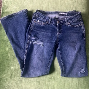 Lågmidjade jeans - Jeans med skitsnygga slitningar, lågmidjade och bootcut. Mycket bra skick Midjemått: 37cm Innerbenslängd: 76cm