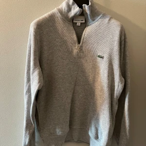 Lacoste half zip grå - Säljer fin half zip från Lacoste, som blivit för liten. Stl XS. Den är cirka 47 cm bred och cirka 60 cm lång. Tröjan är grå och i 100 % bomull. Skick 9/10. 