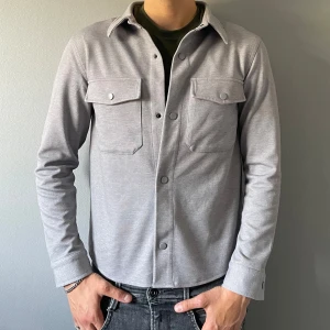 Grå overshiry - Säljer en en riktigt stilren grå Overshirt, passar perfekt nu till hösten. I princip ny endast använd ett fåtal gånger. Passar personer mellan ungefär 175-182. Personen på bilden är 184 För mer bilder och info skicka ett meddelande!
