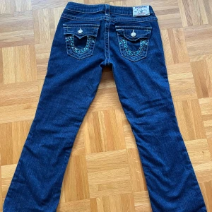 Lågmidjade True Religion jeans - Otroligt snygga lågmidjade mörkblåa bootcut jeans med coola detaljer från true religion. De är i perfekt skick och köpta här på Plick men tyvärr passade de inte mig💓
