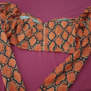 Orangemönstrad topp från PrettyLittleThing - Säljer en cool och trendig topp från PrettyLittleThing i ett ormskinnsmönster. Toppen är i en härlig orange färg med dragkedja framtill. Perfekt för en utekväll eller fest! 🐍✨