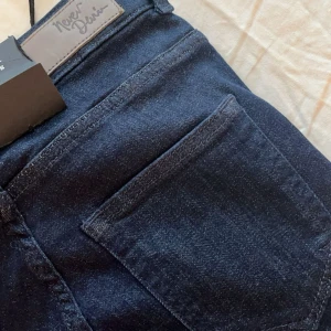 Mörkblå jeans från Never Denim - Snygga mörkblå jeans från Never Denim i storlek XS. De har en klassisk design med knappar framtill. Har aldrig andvänt de här. De är högmidjade.
