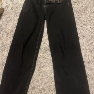 Svarta byxor från Bsat - Snygga svarta byxor från Bsat med kontrasterande vita sömmar. Byxorna har en klassisk femficksdesign och en broderad detalj på bakfickan. Perfekta för en stilren look.