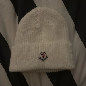 Vit ribbad mössa från Moncler - Säljer en stilren vit ribbad mössa från Moncler. Jag har använt denna en för jag tyckte att den var lite för liten, kan sänka pris vid snabb affär! Hör av er för frågor!