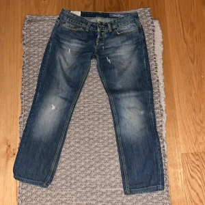 Blå jeans från Dondup - Snygga blå jeans från Dondup i en klassisk straight fit. De har en midwaist och är tillverkade av 100% bomull. Jeansen har slitna detaljer och en knappgylf. Perfekta för en avslappnad stil.