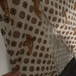 Mönstrad klänning med tigrar - Säljer en unik klänning med ett coolt tiger- och cirkelmönster. Klänningen har korta ärmar och en elastisk midja för en bekväm passform. Perfekt för dig som vill sticka ut med ett djärvt mönster!