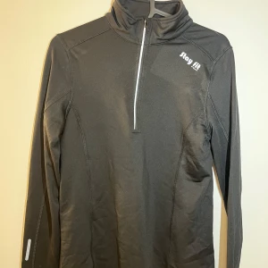 Svart långärmad tröja från Stay Fit - Säljer en svart långärmad tröja från Stay Fit med halv dragkedja framtill. Perfekt för träning och har en sportig look. Tröjan är tillverkad i ett syntetmaterial som andas. Nästan alldrig använd. 