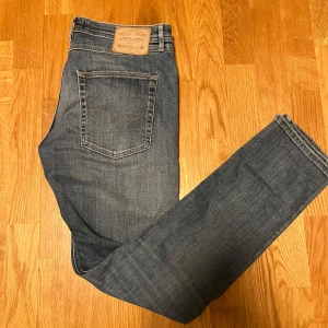 Blå skum fit jeans från Jack & Jones - Snygga blå jeans från Jack & Jones med en klassisk femficksdesign. De har en lätt slitning på knäna för en trendig look. Perfekta för en avslappnad stil. De är i storleken 33/32 och är i nytt skick. Hör av er vid minsta fundering!