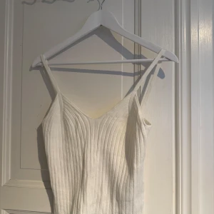 Vit ribbad linnetopp från Envii - Säljer en stilren vit ribbad linnetopp från Envii. Toppen har smala axelband och en enkel design som passar perfekt till sommaren. Perfekt för att matcha med jeans eller kjol för en avslappnad look.