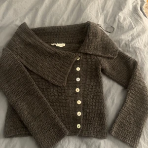 Grå stickad tröja från Zara - Säljer en snygg grå stickad tröja från Zara med stora knappar framtill. Super mysig, använd 1 gång då jag tyckte att den var lite liten på mig. jätte fint skick, som ny.