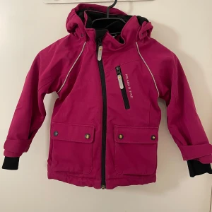 Rosa jacka från Polarn O. Pyret - Säljer en snygg rosa jacka från Polarn O. Pyret i storlek 104. Jackan har en praktisk dragkedja framtill, huva och flera fickor med knappar. Perfekt för aktiva dagar utomhus!