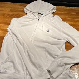 Vit Polo Ralph Lauren Zip - Tja! Säljer min vita zip från Polo Ralph Lauren. Säljer pga att den inte används. Tröjan är i 10/10 skick men använd. Har en qr kod som scannar och kommer direkt till Ralph Laurens hemsida. Skriv gärna vid fler frågor. 