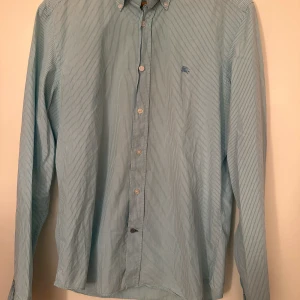 Burberry  - Burberry skjorta mint grön. Super fint skick utöver en knapp som är skadad men funkar felfritt. Pris 890kr.