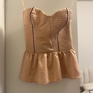  Beige korsett likande med volangdetalj   - Säljer denna snygga korsett liknande toppen vet dessvärre inte vad märket ör.