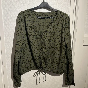 Mörkgrön med svart mönster tröja  - Fint skick. Knytning nertill och knappar. 