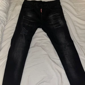 Svarta dsquared2 jeans - Snygga svarta jeans med slitningar på låren och knäna. De har en slim passform och är midwaist. Perfekta för en trendig look.