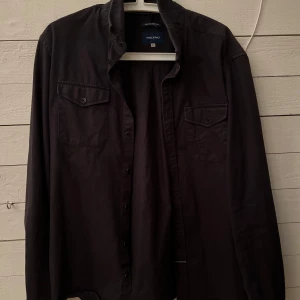 Svart skjorta från Blend - Snygg svart skjorta från Blend i storlek L. Skjortan har långa ärmar och två bröstfickor med knappar. Perfekt för en stilren look. Tillverkad i ett bekvämt material som passar bra till olika tillfällen. Passar som en vanlig skjorta och om man vill ha ex en hoodie under 