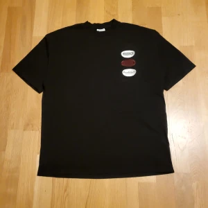 Svart t-shirt från Hoodrich - Säljer en svart t-shirt från Hoodrich med tryck på bröstet och ryggen. T-shirten är tillverkad i 100% bomull och har korta ärmar. Perfekt för en casual look. Har ett fåtal märken från urtvättning. För föer bilder eller information kontakta .