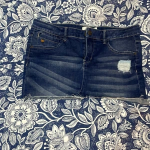 Mini skirt från Name It - Säljer en cool blå jeanskjol från Name It. Kjolen har en sliten look med en liten reva på framsidan och rå kant nedtill. Perfekt för en avslappnad stil. 🦋