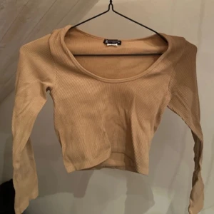 Beige ribbad långärmad topp - Säljer en beige ribbad långärmad topp med rund hals. Perfekt för lager-på-lager eller som den är. Enkel och stilren design som passar till mycket. Knappt använd, går inte ändra men bra skick. Kortare modell