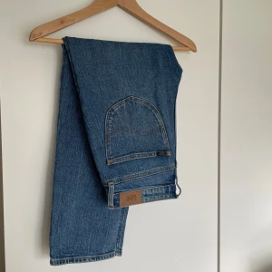 Blå jeans från Lee - Snygga blå jeans från Lee med klassisk design. De har en rak passform och är tillverkade i slitstarkt denim. Perfekta för en avslappnad stil. Storlek W27/L33