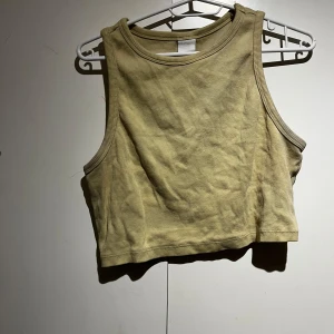 Gul ribbad linnetopp - Säljer en gul ribbad linnetopp i croppad modell. Toppen är ärmlös och har en rund halsringning. Perfekt för en avslappnad stil.