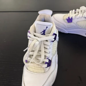 Jordan 4 metallic purple - Snygga vita sneakers med lila detaljer från Nike. Skorna har snörning och en ikonisk design med meshpaneler för extra ventilation. Perfekta för en sportig look. De är typ helt nya har använt de tre gånger. De är i jätte bra skick. Storlek 36 eur 