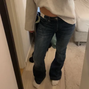Blå jeans med bootcut - Säljer ett par snygga blå jeans med bootcut-stil dom är mid waist och helt nya. De har en klassisk femficksdesign och en knappgylf. Perfekta för en avslappnad look.