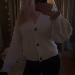 Vit kofta med knappar - Mysig vit/beige kofta med stora knappar framtill. Perfekt för kyliga dagar och ger en avslappnad look. Koftan har en v-ringad design och långa ärmar💗