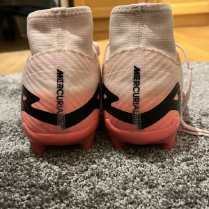 Nike fotbollsskor i rosa och svart - Säljer ett par Nike fotbollsskor i rosa med svarta detaljer och snörning. Skorna har en hög krage och dobbar för bra grepp på planen. Perfekta för fotbollsspelare som vill ha stil och funktion. storlek EUR 43