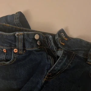 Mörkblå jeans med knappar (flared) - Snygga mörkblå jeans med en klassisk design och knappar framtill. De har en rak passform och är perfekta för en avslappnad stil. Jeansen har också praktiska bakfickor.