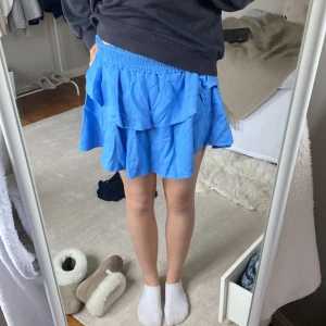 Blå volangkjol - Snygg blå kortkjol med volanger. Perfekt för en somrig look. Elastisk midja för bekväm passform.aldrig använd