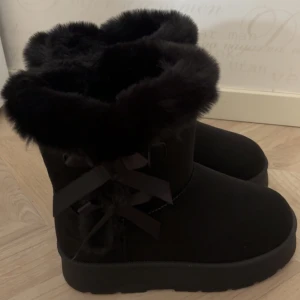 Helt nya svarta boots/uggs - Svarta boots med dekorativa rosetter på sidan. Som sagt, helt nya och inte använda. Kontakta mig ifall due instresserad 😛