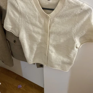 Beige kortärmad kofta - Säljer en söt beige kofta med korta ärmar och knappar framtill. Använt endast 2 gånger 