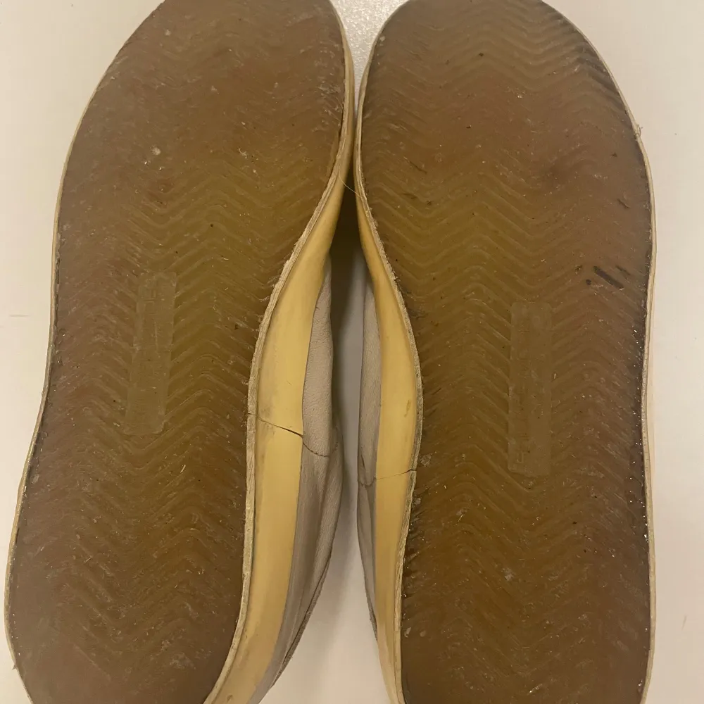 Säljer ett par beige sneakers med en unik blå och grön detalj på sidan. Skorna har vita snören och en gulaktig sula som ger dem en retro look. Perfekta för en avslappnad stil. Skorna är i relativt bra skick endast sulorna som gick av för nån månad sen men jag limade med riktigt sko lim och nu håller dom men kan säkert lossna lite om 2-3 månader. Hör av dig vid minsta funderingen👍🏼. Kengät.
