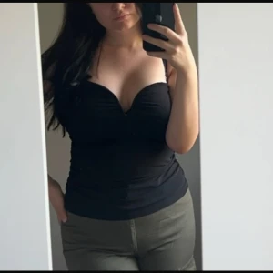 Svart korsettopp - Snygg svart korsettopp med en tight passform och djup urringning. Perfekt för en kväll ute eller en speciell tillställning. Toppen har en stilren design som framhäver figuren.