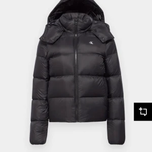 Svart dunjacka från Calvin Klein - Snygg svart dunjacka från Calvin Klein med huva och dragkedja framtill. Jackan har en klassisk pufferdesign och är perfekt för kyligare dagar. Den har långa ärmar och en diskret logga på bröstet. Pris : 700 köpt för cirka 3000! Använd 1 vinter och säljer pågrund av att jag köpt en ny. Lite av Ck märket på bröstet har försvunnit o därför kan pris diskuteras
