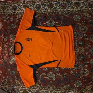 Nederländerna tröja från Nike - 02 Nederländerna tröja från Nike, det finns tecken på användning, en svart prick som inte går bort i tvätt är precis under Nike emblemet och dri-fit loggan är sliten (se bilder)