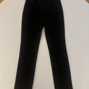 Svarta byxor - Snygga svarta byxor med en klassisk design. Perfekta för en stilren look. Byxorna har en rak passform och är tillverkade i ett bekvämt material.
