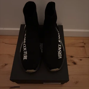 Versace skor - Versace jeans couture skor (strumpskor). Dessa skor är i gott skick, bekväma och enkla att få på sig. Skorna är äkta och inköpta från Urban Modern. Skokartong, dustbag och påse ingår.  Storlek 43