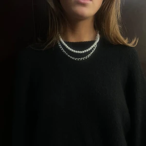 015 - Elegant dubbelradigt halsband med vita pärlor. Perfekt för att ge en klassisk touch till din outfit. Halsbandet har en tidlös design som passar till många tillfällen.