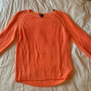 Orange stickad tröja - Säljer en härlig orange stickad tröja med rund hals och långa ärmar. Tröjan har ribbstickade muddar vid ärmslut och nederkant, vilket ger en snygg passform. Perfekt för kyligare dagar!