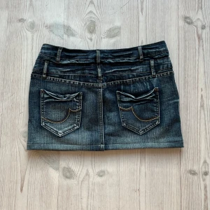 Lågmidjad jeanskjol  - Mörkgrå lågmidjad jeanskjol från Sublevel som jag har sytt upp från en längre kjol. Storlek M, passar även S. Tvärs över midjan är det 39 cm och den är 33 cm lång. Fint skick. Använd gärna köp nu!