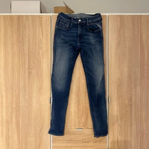 Replay jeans - Snygga mörkblå replay jeans med lätt slitna detaljer och klassisk femficksdesign. De har en knapp och dragkedja framtill. Perfekta för en avslappnad stil.