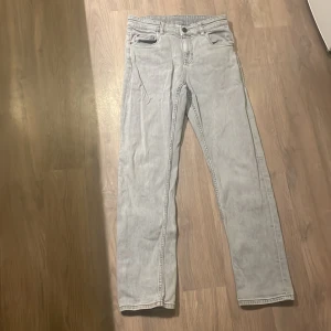 Ljusgrå jeans från Kappahl - Snygga ljusgrå jeans från Kappahl i storlek 158. De har en klassisk straight femficksdesign och stängs med dragkedja och knapp. Perfekta för en avslappnad stil.