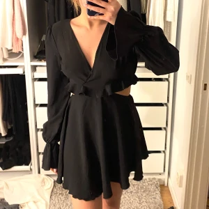 Svart klänning med volangdetaljer - Nelly klänning som inte finns längre. 🤗Snygg svart klänning med v-ringning och volangdetaljer. Ryggen är lite öppen. Den är aldrig använd men saknar prislapp. 