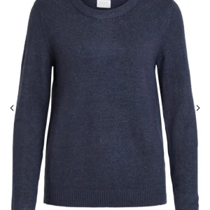 Mörkblå stickad tröja  - Säljer en stilren mörkblå stickad tröja från VILA. Tröjan har en rund halsringning och långa ärmar, perfekt för kyligare dagar. Den är enkel och klassisk i designen med ribbade kanter vid ärmslut och nederkant. Jag skulle säga att den är mer en M. 