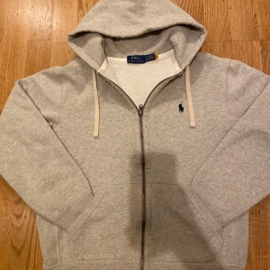 Grå hoodie från Ralph Lauren - Hej, säljer denna Ralph lauren zip tröjan!⭐️ Tröjan är i utmärkt skick utan några defekter! Nypris 2300kr! ❌💵  Mitt pris 1100kr!✅⭐️ Priset är ej hugget i sten så kom med prisförslag. Jag kan ge rabatt vid snabb affär!🏬  Om ni undrar något mer kan ni höra av er eller kolla på care of carles sida där den finnns!😁