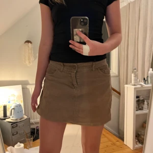 Brun kortkjol - Säljer en snygg brun kortkjol med klassisk design. Kjolen har fickor både fram och bak samt en knapp- och dragkedjestängning. Perfekt för en avslappnad stil.🙌🙌